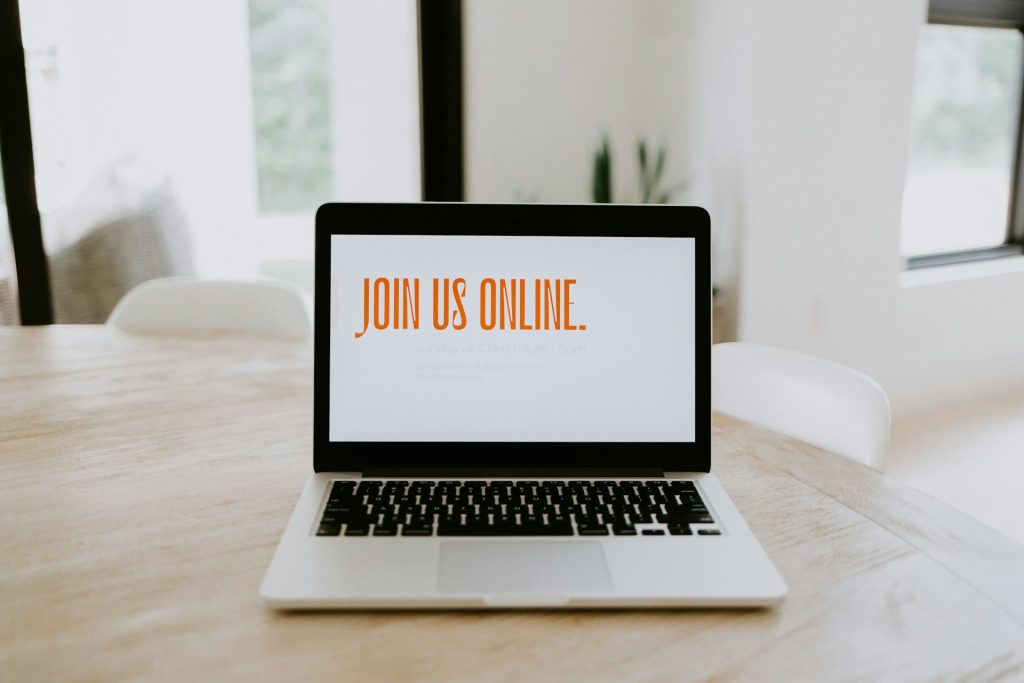 open laptop on table with text, "Join us Online" on monitor